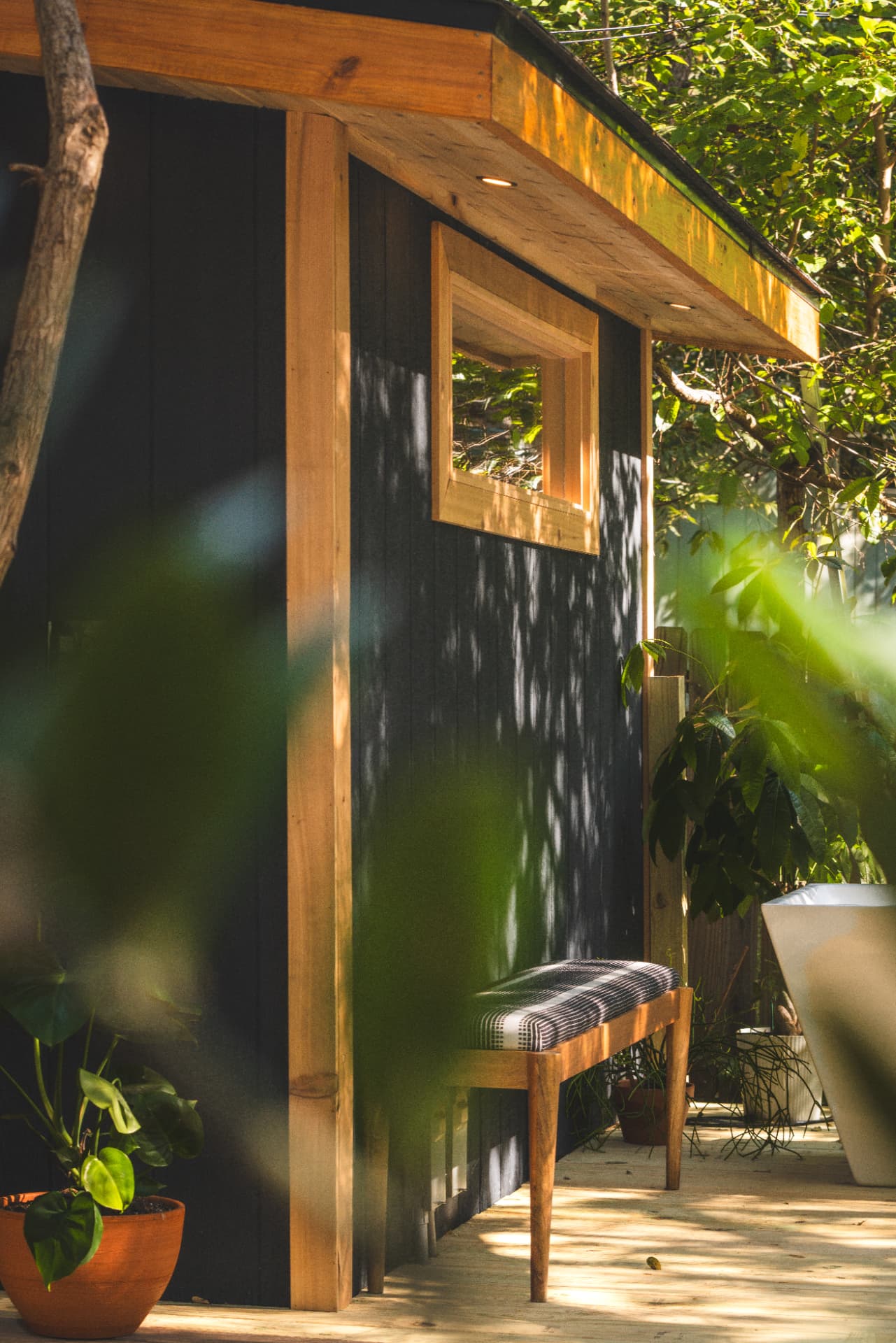 Cedar bench on the deck beside the sauna in dappled afternoon shade