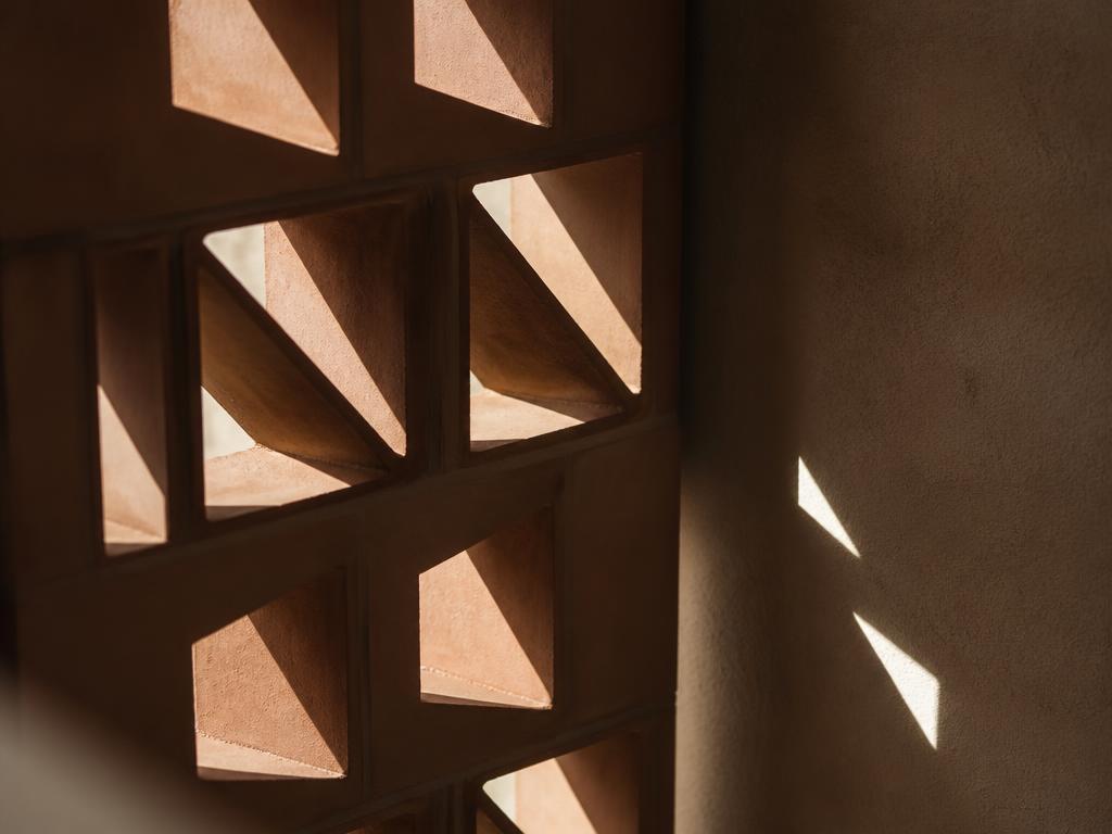 Structural terracotta blocks transmitting natural daylight across a plaster wall